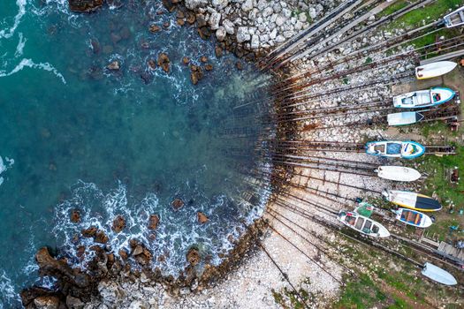 Aerial top view at the small bay and pier with fishing boats on the shore