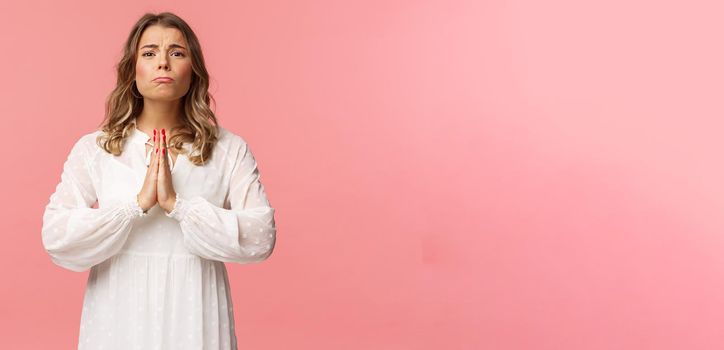 Portrait of hopeful clingy girlfriend, blond girl begging for favour in white dress over pink background, sobbing make cute eyes, pleading or praying, say please, want something badly.