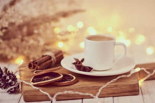 Cup of coffee with garland lights and decoration on table. Cozy home concept