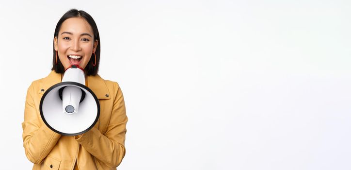 Attention announcement. Image of asian woman shouting in megaphone, recruiting, searching people, sharing information, standing over white background.