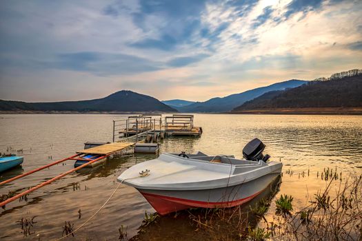 Moored wooden boat after sunset at the lakeshore