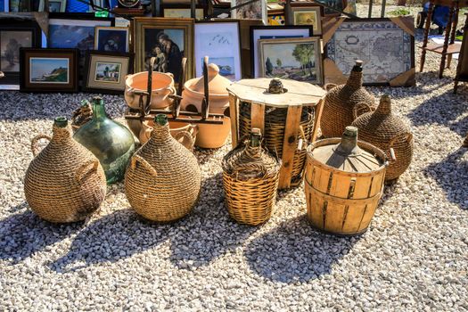 Guardamar, Alicante, Spain- April 3, 2022: Glass carafes covered with raffia for sale at El Fogon antiques flea market in Guardamar