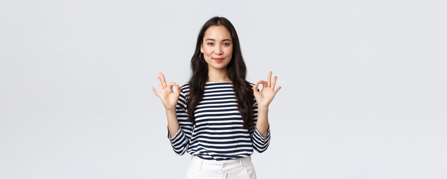 Lifestyle, beauty and fashion, people emotions concept. Satisfied good-looking female guarantee quality of product, recommend advertisement, showing okay sign, say no problem, have all under control.
