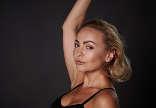 Close-up side portrait of an attractive middle aged European woman confidently looking at camera isolated over black background with copy ad space