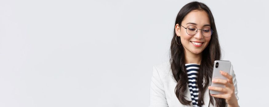 Business, finance and employment, female successful entrepreneurs concept. Close-up of stylish modern businesswoman in suit and glasses messaging, using mobile phone.