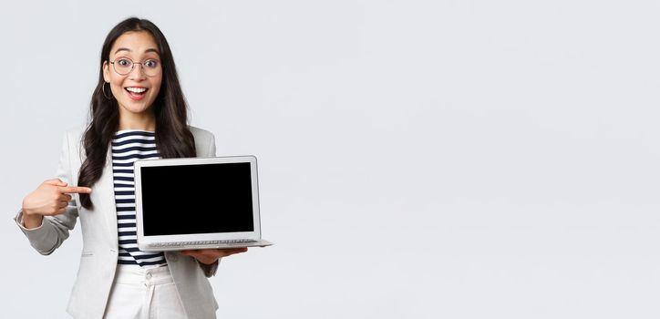 Business, finance and employment, female successful entrepreneurs concept. Enthusiastic office manager showing her presentation on laptop, pointing at screen and smiling amused.