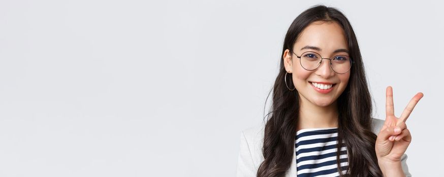 Business, finance and employment, female successful entrepreneurs concept. Close-up of friendly outgoing asian office employee showing peace sign and smiling optimistic, have all under control.