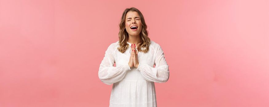 Portrait of hopeful, desperate young beautiful blond woman in white dress, whining, complaining cruel life, praying god make dream come true, crying heart out during pleading, ask please.