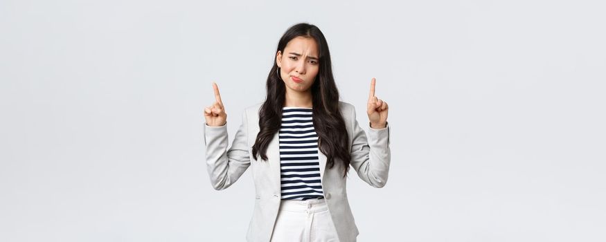 Business, finance and employment, female successful entrepreneurs concept. Skeptical and disappointed businesswoman, asian office lady grimacing displeased and pointing fingers up.