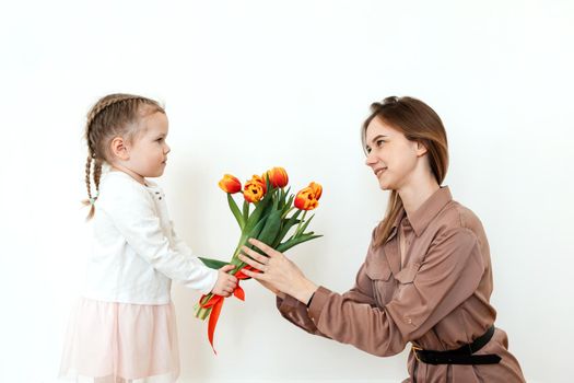 Happy daughter congratulates mom with tulips.