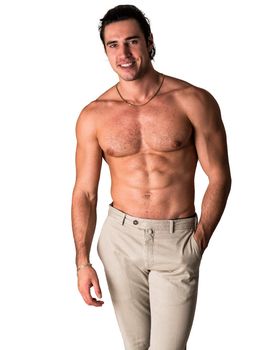 Three quarters shot of handsome shirtless athletic young man in pants, smiling to camera in studio shot, isolated on white background