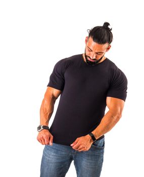 Handsome, muscular man showing and looking at blank empty t-shirt as if to show something printed on it, looking down, isolated on white