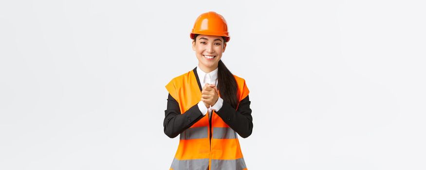 Thankful successful asian female architect greet investors or clients at construction area, wearing safety helmet and jacket, shaking clenched hands in appreciation, being grateful for trust.