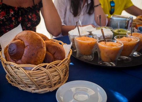 Sicilian granita, slush or crushed-ice drink, with traditional Italian pastry for breakfast on table in a basket