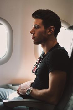 Side view of handsome young man against plane window sitting