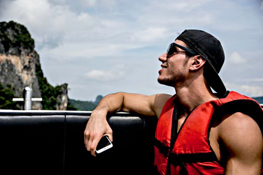 Side view of a young man on a raft or boat relaxing in the sea in Phuket, Thailand
