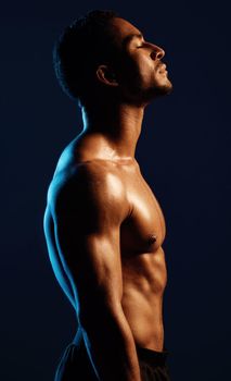 Studio shot of a fit young man posing against a black background.