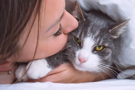 Beautiful woman kissing funny grumpy cat. People and pets love and friendship. Cat and owner together. Cat lover. High quality photo