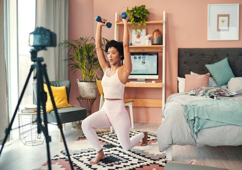 Shot of a young woman recording herself while exercising at home.