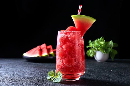 Ripe watermelon noisette balls with soda in glass on dark background. Refreshing summer drink.