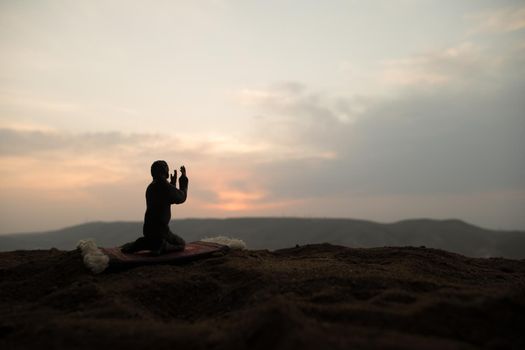 Silhouette of muslim prayer on sunset. Ramadan Kareem background. Praying people. Selective focus