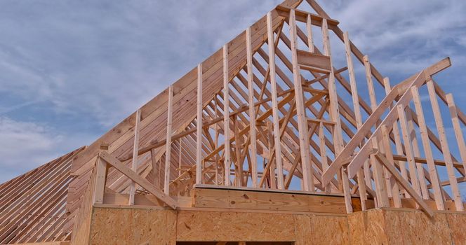 Framing beams of new home under construction with wooden roof trusses