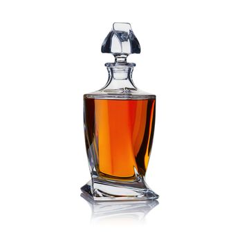A full crystal whisky decanter, with amber cognac strong alcohol, shot on white, with a small reflection.