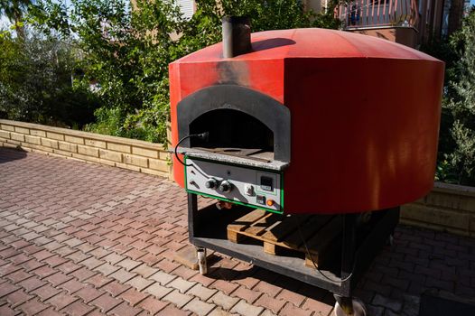 Large domed red metal outdoor pizza oven