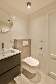 The interior of the bathroom with a toilet and a ceramic sink under a round mirror