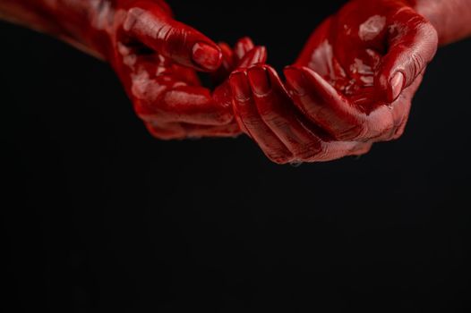 Women's hands in blood on a black background