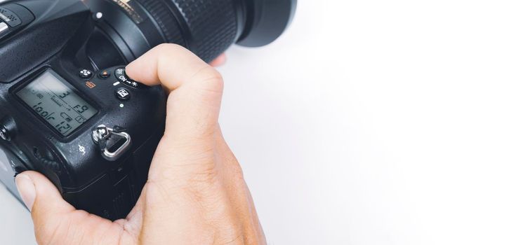 Photographer hand about to click the shutter button of digital DSLR camera with a copy space and white background