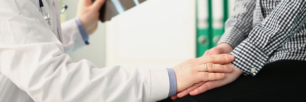 Close-up of medical worker support female patient holding x ray result. Doctor in medical gown hold hand on clients hand. Bad news, illness, medicine, healthcare concept. Blurred background