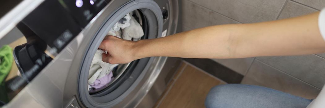 Top view of woman loading washing machine with dirty clothes, modern device keep clothes clean and smelly. Household, bathroom, domestic chores, cleaning day concept