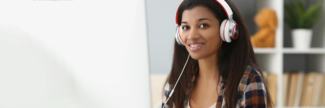 Portrait of pretty young office worker in headset, making notes, search information online. Student in university, prepare for exam, learn new material. Job, uni, study concept. Blurred background