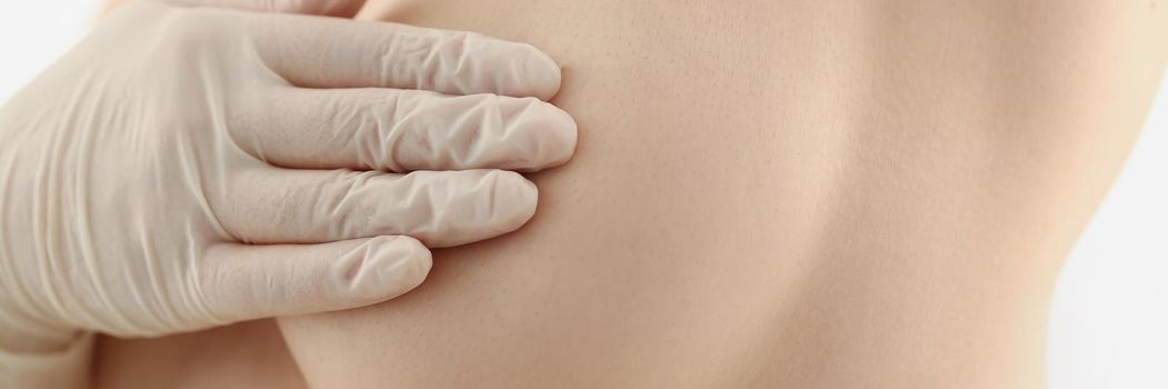 Close-up of woman preparing for breast operation, topless female cover boob with hand in glove. Desire for breast augmentation, surgery made in clinic. Beauty, plastic, cosmetic surgery concept