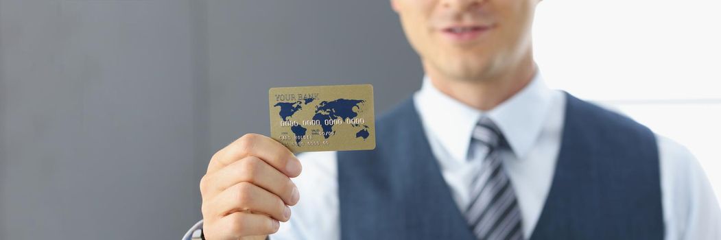 Portrait of smiling handsome businessman standing with credit card, successful worker in classic suit. Achievement, career, wealth, success, banking, opportunity concept