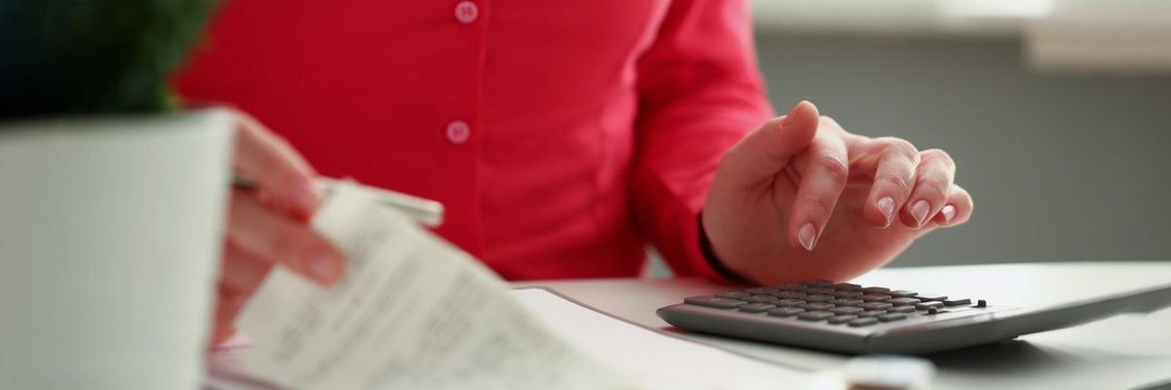 Close-up of office worker calculate financial situation in company, female accountant use calculator for work. Checks and bills on desk. Finance, economy, banking, prepare report concept