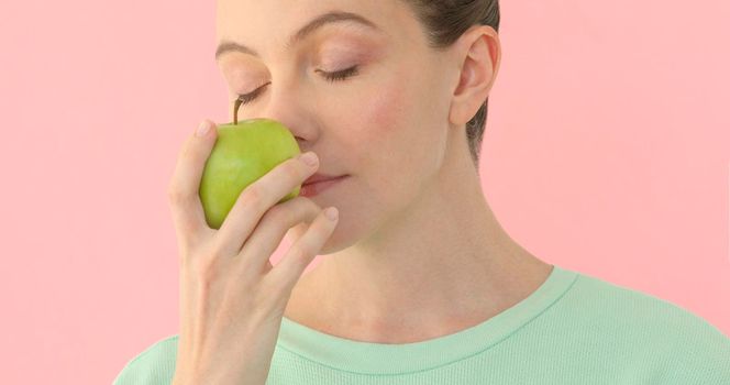Woman holds green apple enjoys smell fruit