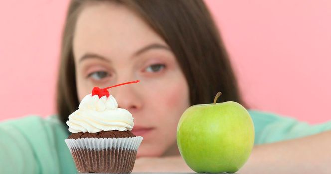 Girl longly makes choice between cake apple begins eat apple