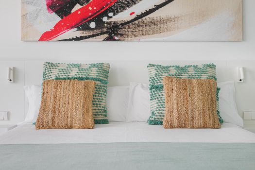Beautiful and comfortable pillows in bedroom of a hotel with abstract picture above the bed
