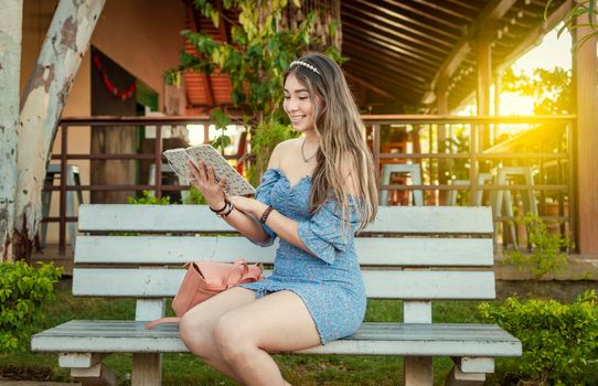 A cute girl sitting on a bench reading a book, pretty young latin girl reading a book on a bench