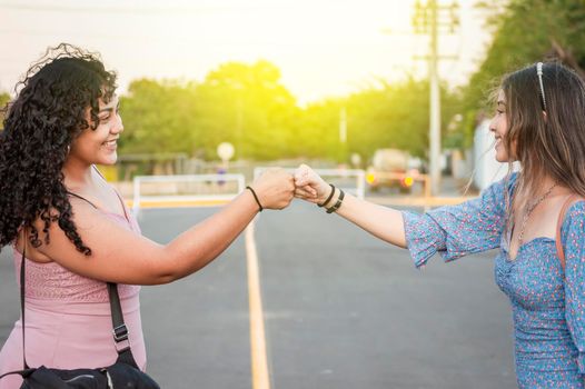 Two girls shaking fist, Two woman clashing their fists, image of two girl bumping their fists in a friendly way