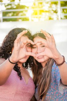 Close up of two girls making a heart shape, two friends together forming a heart, love hands sign