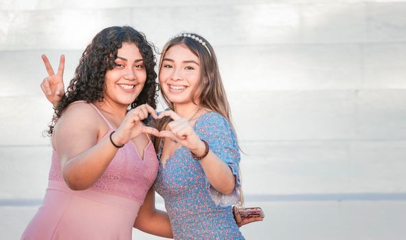 Close up of two girls making a heart shape, two friends together forming a heart, love hands sign