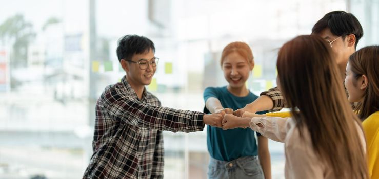 diverse group of asian business partner fist bump in modern office. Colleague partnership teamwork, university student, congratulation event, job or mission accomplish concept.
