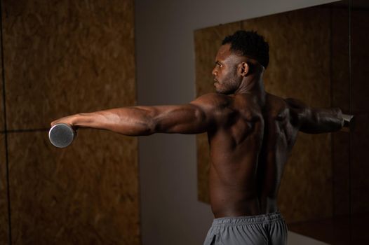 Attractive african american man doing arm exercises with dumbbells