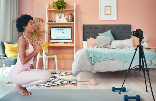 Shot of a young woman recording herself while exercising at home.