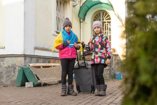 Ukraine military migration. two little girls with a suitcase. Flag of Ukraine, help. Crisis, military conflict.