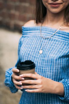 A female in a striped jumpsuit posing with a coffe cup. summertime