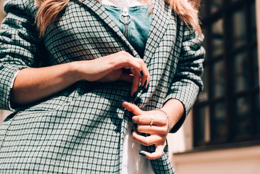 beautiful female tanned hands with blue manicure and element of stylish checkered coat